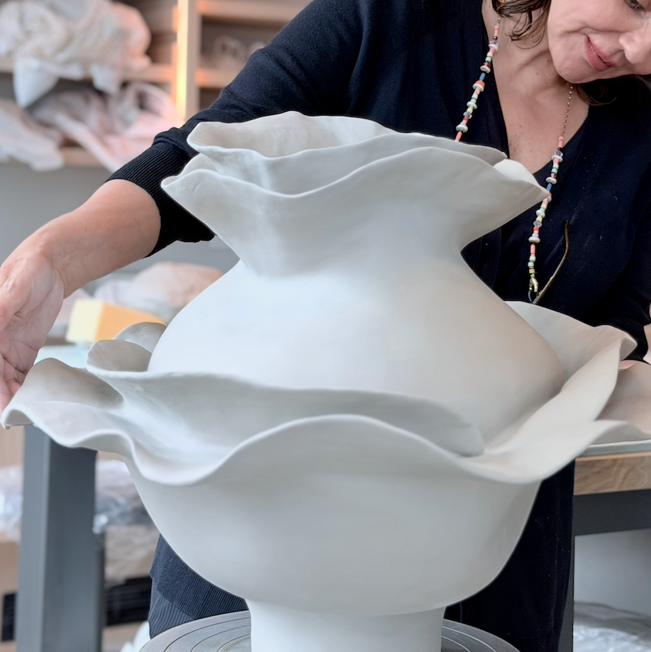 Person holding a large ceramic vase in a workshop setting