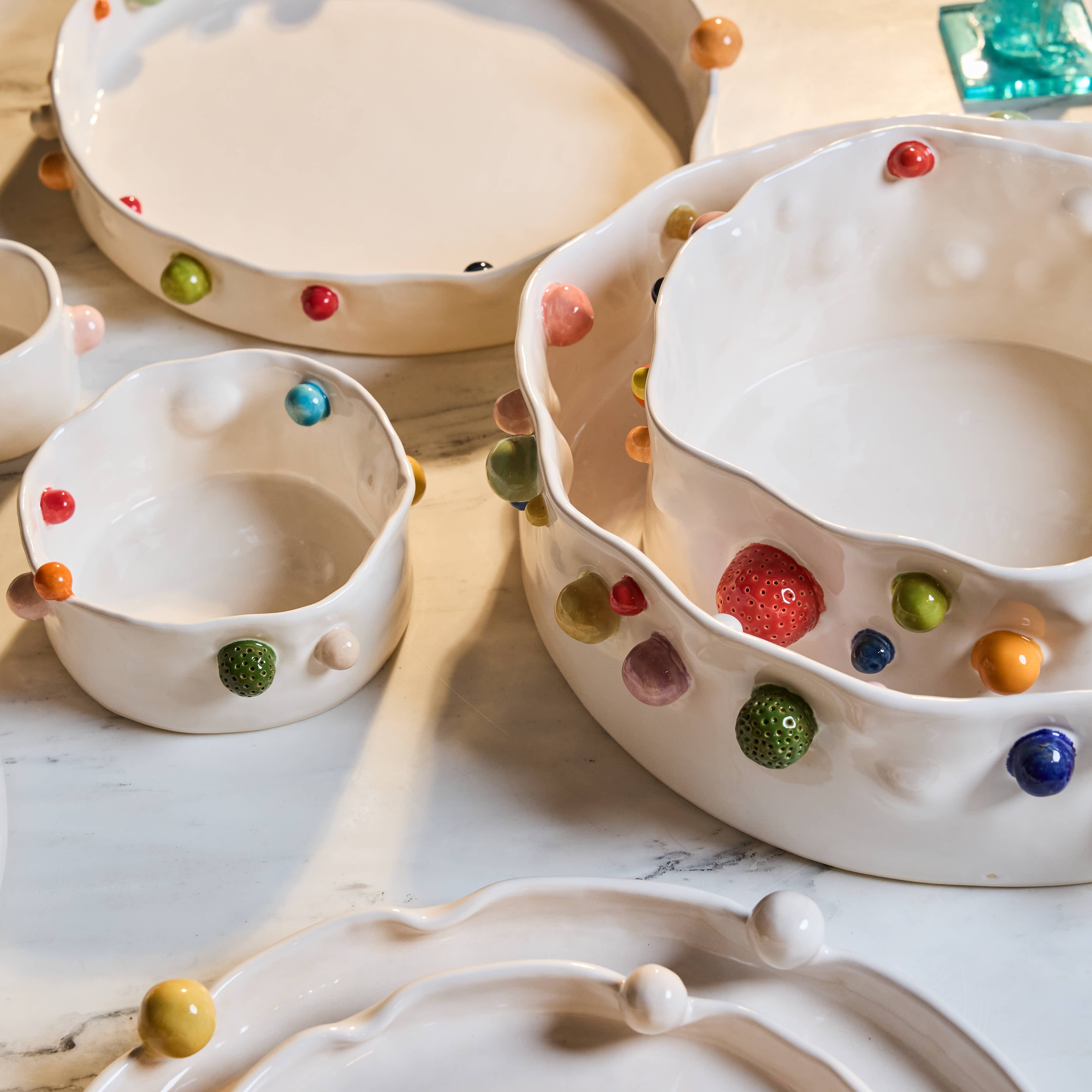 Ceramic bowls with colorful spherical decorations on a light wooden surface