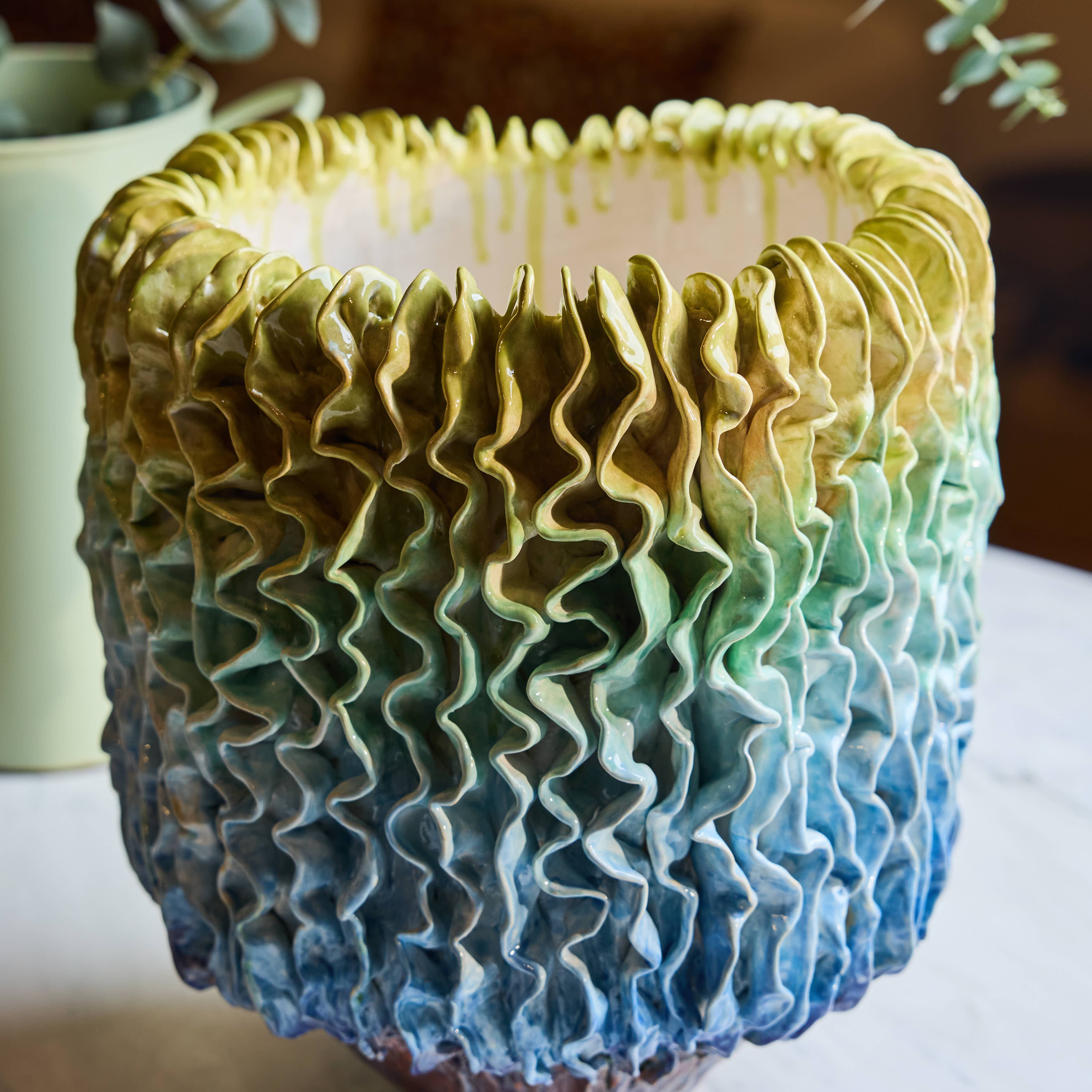 Ceramic candle holder with wavy texture and gradient color on a wooden surface.
